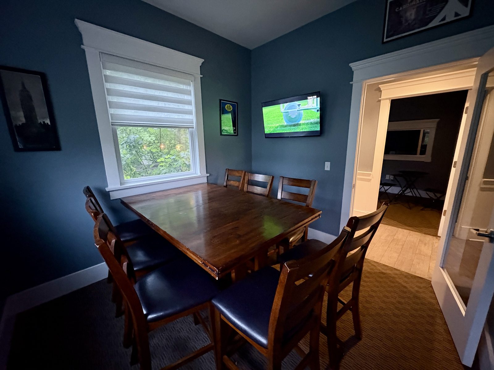 The dining room — long wood table, TVs, den beyond