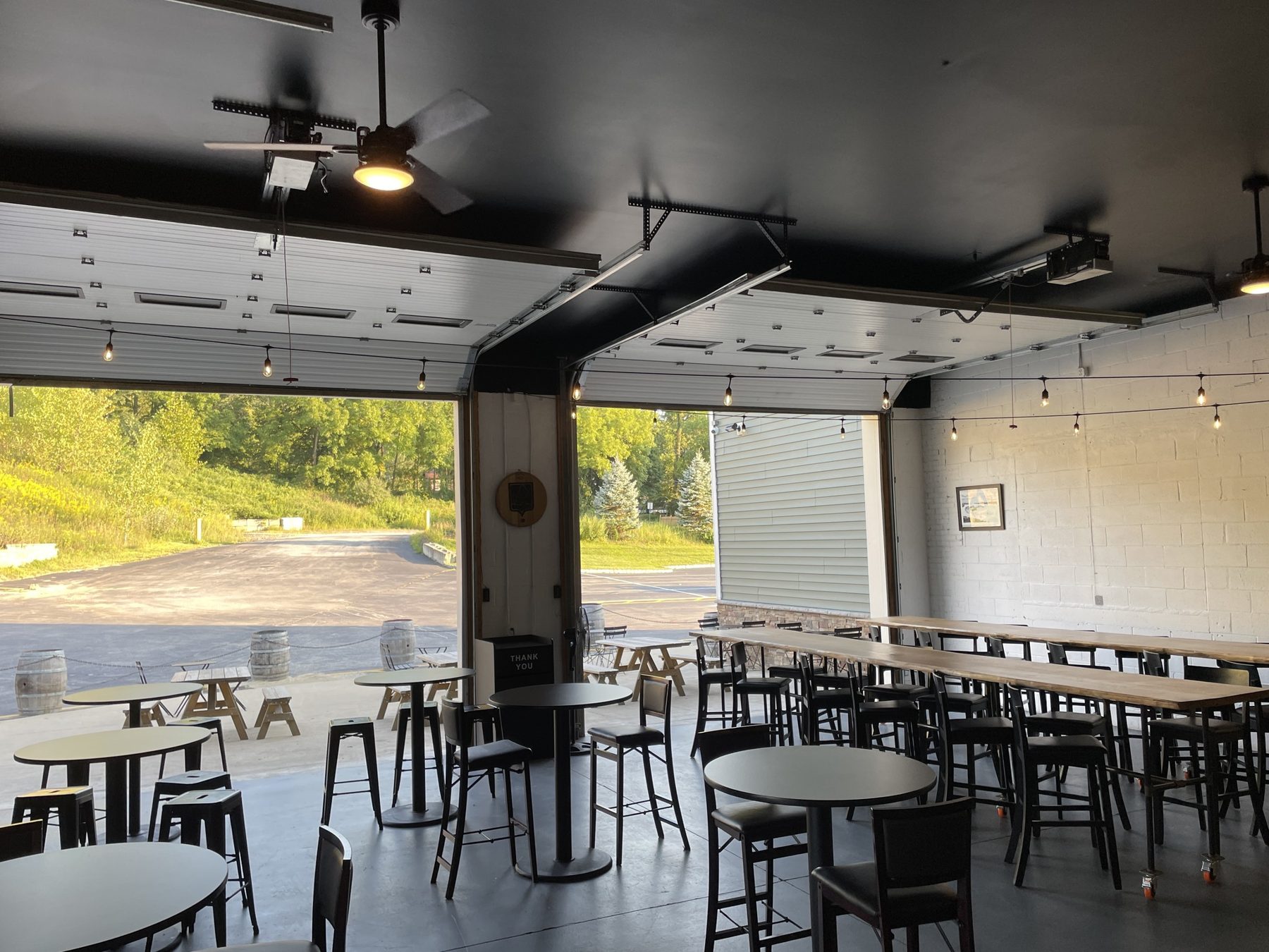 The long community tables in the taproom, garage doors open to the hillside