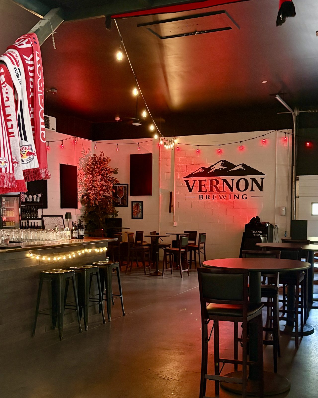 The tasting room lit red for a match day, scarves overhead